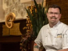 Chef Matthew Bishop sitting in a chair in his chef's uniform.
