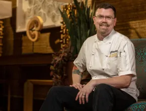 Photo of chef Matthew J. Bishop sitting in a chair in his chef's uniform
