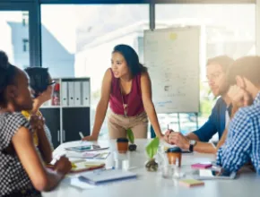 image of a woman leading a discussion at a small board table