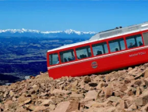 Pikes Peak Cog Railway train going up a mountain.