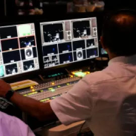 Man working audiovisual equipment for a hybrid meeting.