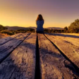 Image of woman sitting at the end of a dock.