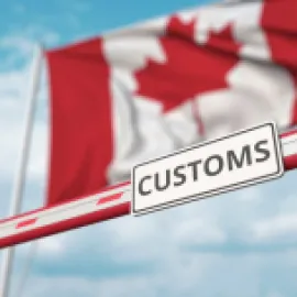 Canada's flag waves above a customs sign.