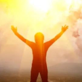 Image of person lifting arms with sun in the background.