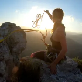 Woman climbing a cliff with a rope.