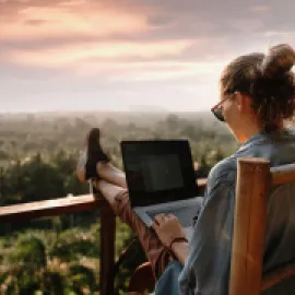 Photo of woman working on laptop outside.