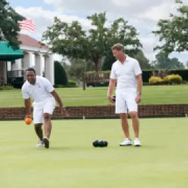 Image of two men lawnbowling at Pinehurst resort, in white shorts and teeshirts.