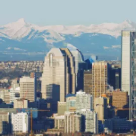 Photo of Calgary skyline with snow-capped mountains in the distance.