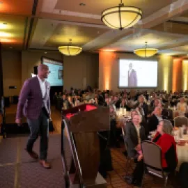 Meeting room full of attendees and a stage with a speaker in Lincoln, Nebraska