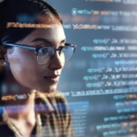 Image of woman looking at a computer screen with code passing by.