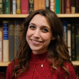 Photo of Taylor Smith standing in front of a wall of books.