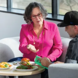 Photo of Tracy Stuckrath sitting on a couch, talking with chef.