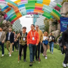 Photo of attendees attending Dreamforce 2024, walking under a rainbow-colored arch.