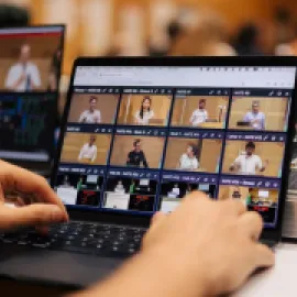 Image of two hands on a laptop, operating SlidesLive's NATE software system.