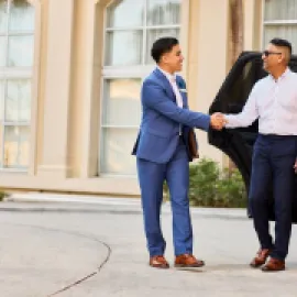 Photo of a Gaylord Hotels Celebrity Services staff member greeting a guest as he exits a black SUV.