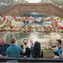 A group of people on a gondola toasting each other on Lake Carolyn.