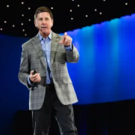 Photo of Steve O'Malley on stage, pointing at the audience.