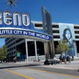 Photo Biggest Little City in the World sign with a mural on a parking garage on the right.