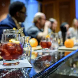 Photo of a cocktail on a bar with bar patrons behind it.