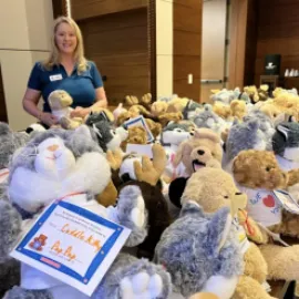 Woman standing with a bunch of stuffed animals for charity.