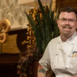 Chef Matthew Bishop sitting in a chair in his chef's uniform.