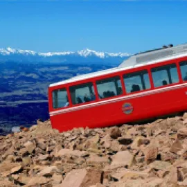 Pikes Peak Cog Railway train going up a mountain.