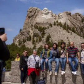 People posing for a photo in front of Mount Rushmore.
