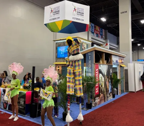 On the show floor, the United States Virgin Islands drew attention with steel drums, dancers and a surprisingly nimble fellow on stilts. Credit: Rob Carey. 