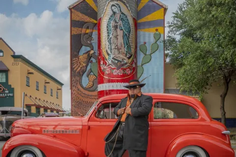 Zoot Suiter in front of celebrated late artist Jesse Treviño’s “Veladora” mural at San Antonio’s Guadalupe Cultural Arts Center, 2023.