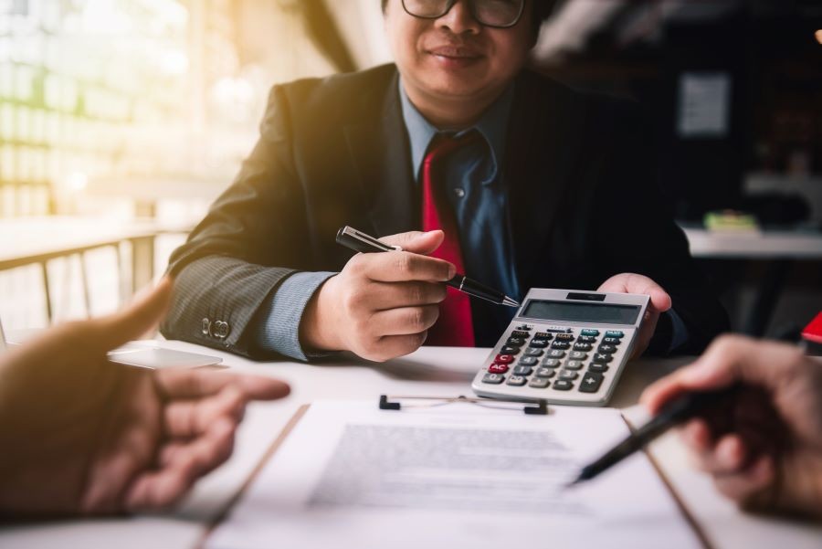 Person with a calculator examining a contract.