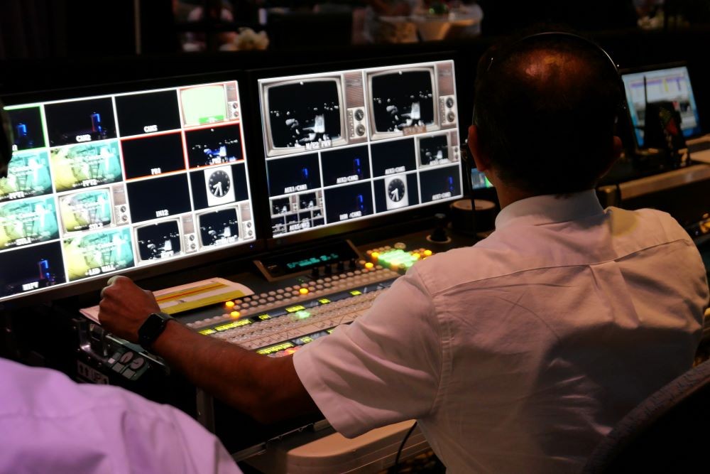 Man working audiovisual equipment for a hybrid meeting.