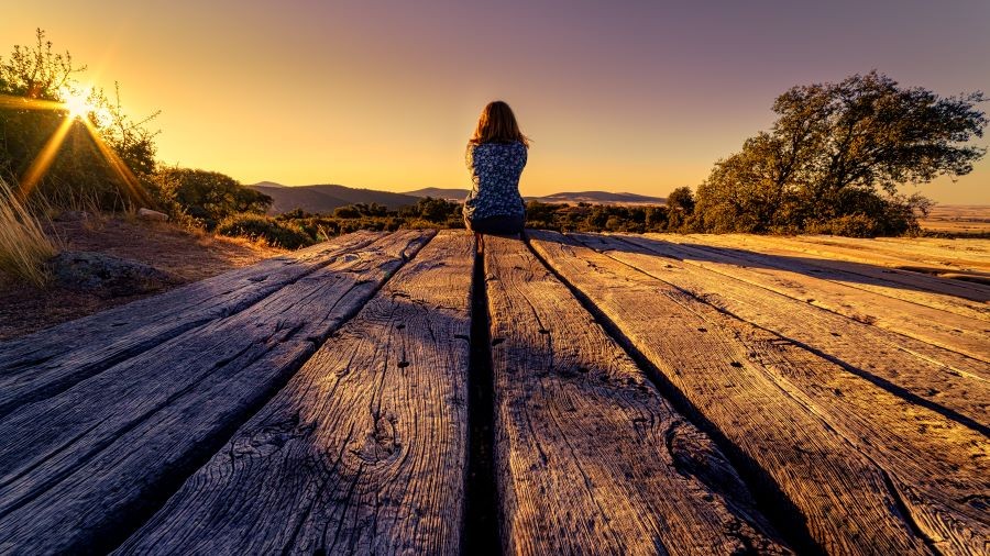 Image of woman sitting at the end of a dock.