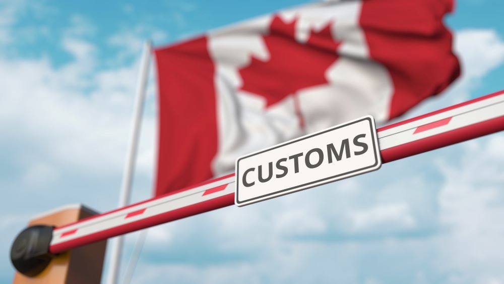 Canada's flag waves above a customs sign.