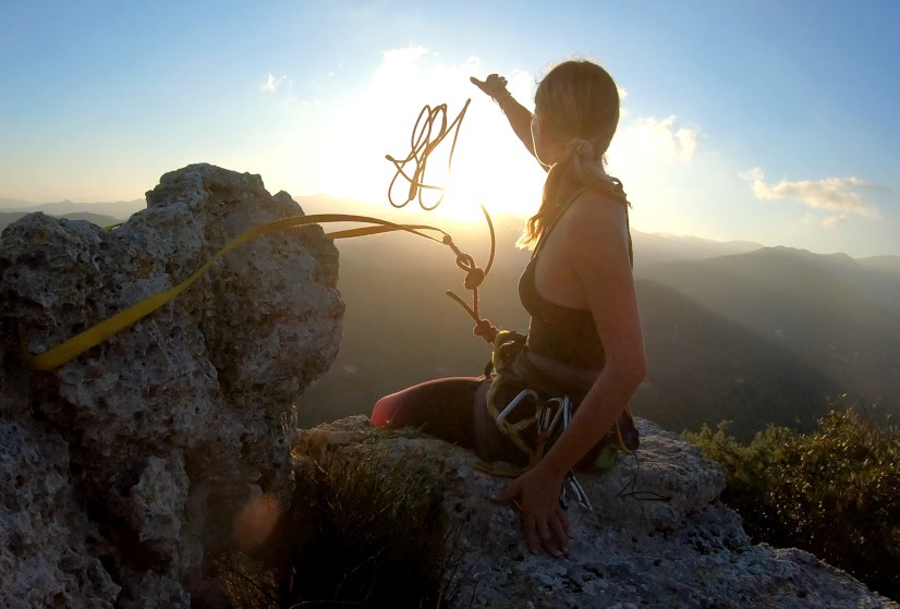 Woman climbing a cliff with a rope.