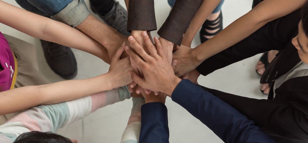 Image of diverse arms locking hands in a circle.