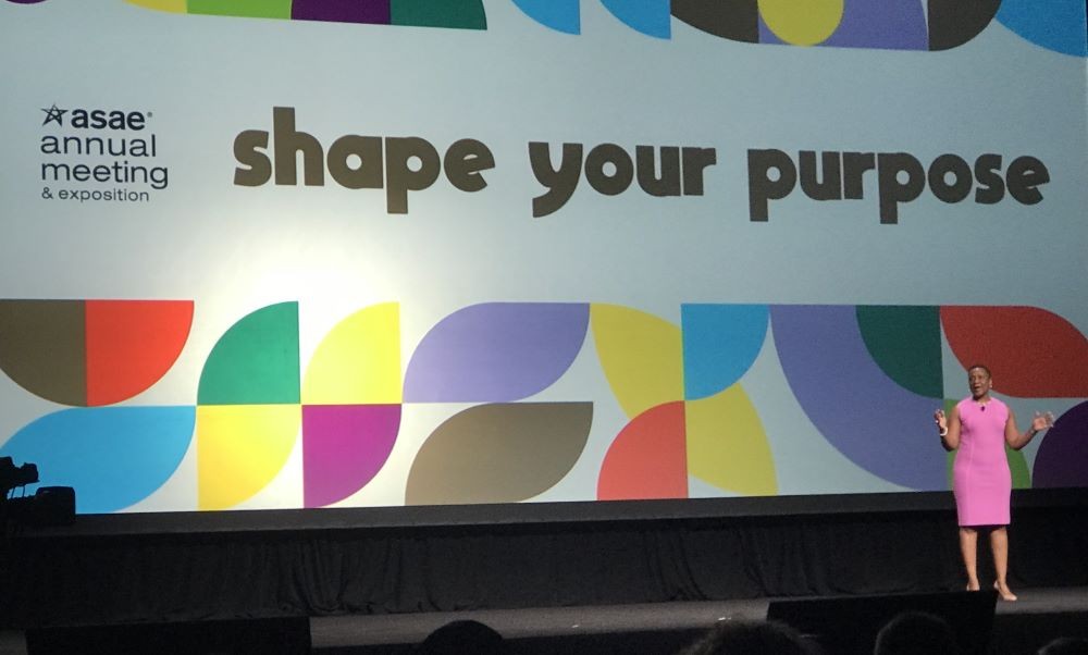 Photo of ASAE President and CEO Michelle Mason on stage at the association's annual conference, with the conference logo Shape Your Purpose on the screen behind her.