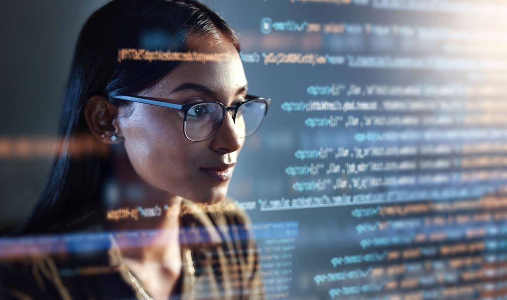 Image of woman looking at a computer screen with code passing by.