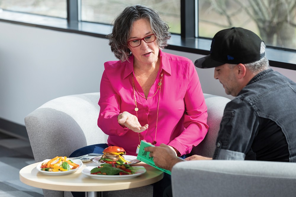 Photo of Tracy Stuckrath sitting on a couch, talking with chef.