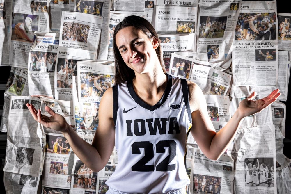 Caitlin Clark (22) shrugs in front of wall of newspaper articles about her during Hawkeyes women's basketball media day, Wednesday, Oct. 4, 2023, at Carver-Hawkeye Arena in Iowa City, Iowa.