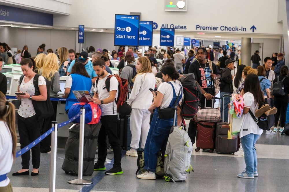 Photo of frustrated travelers standing in line at an airline check-in counter.