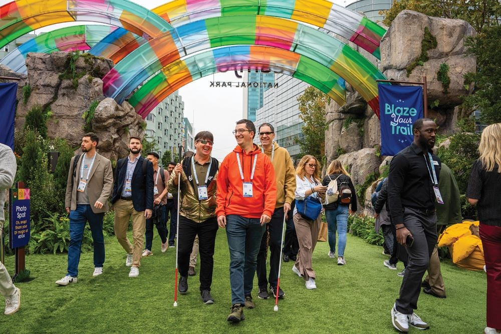 Photo of attendees attending Dreamforce 2024, walking under a rainbow-colored arch.