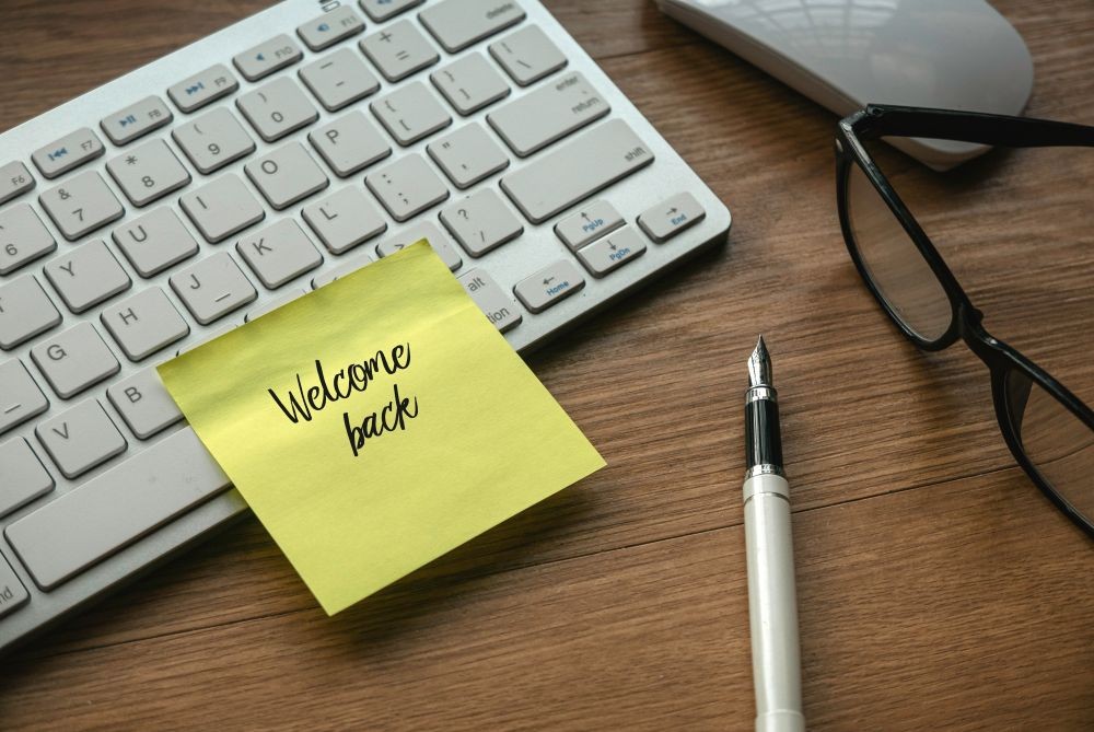 A graphic of a computer keyboard with a Post-It reading Welcome Back on it.
