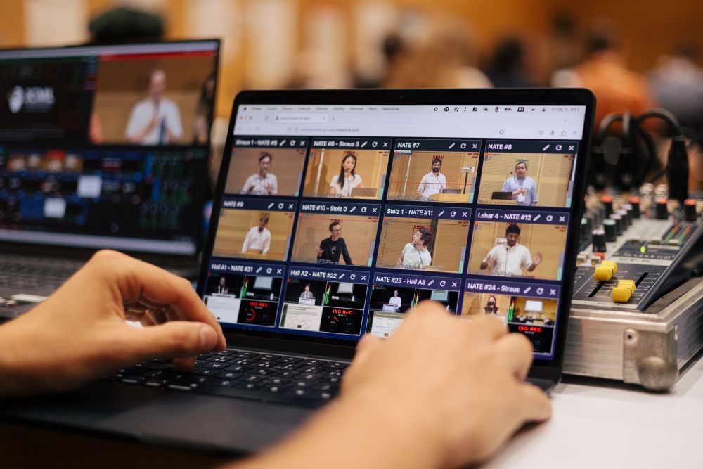 Image of two hands on a laptop, operating SlidesLive's NATE software system.