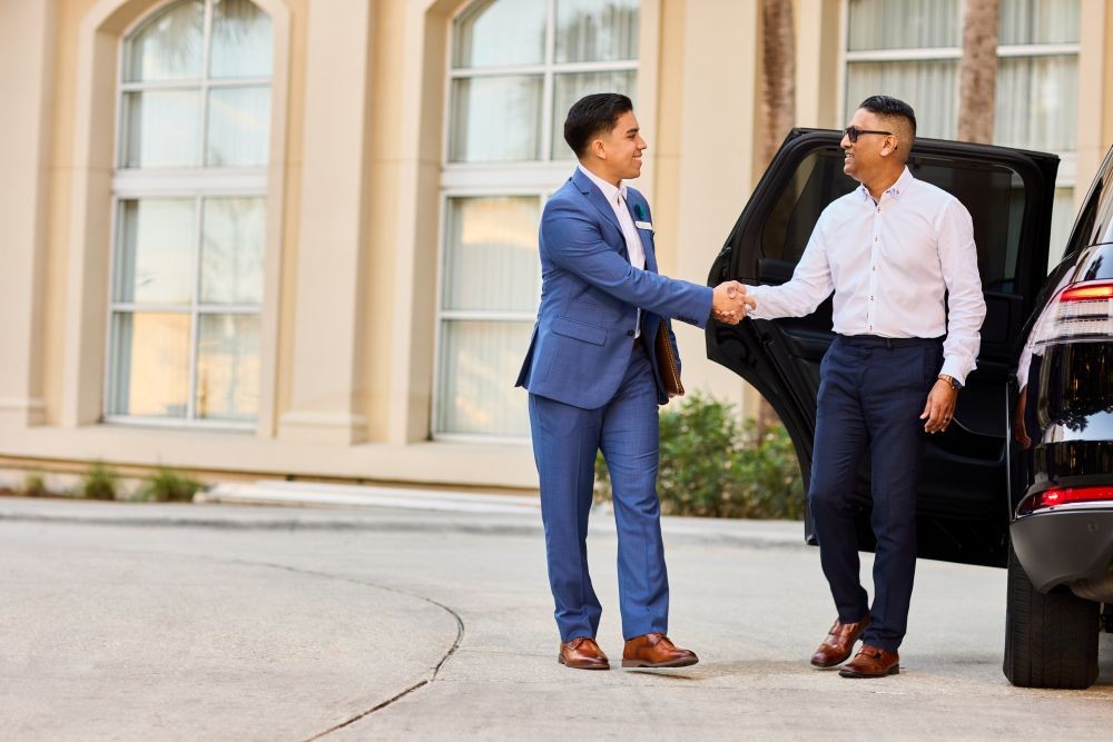 Photo of a Gaylord Hotels Celebrity Services staff member greeting a guest as he exits a black SUV.