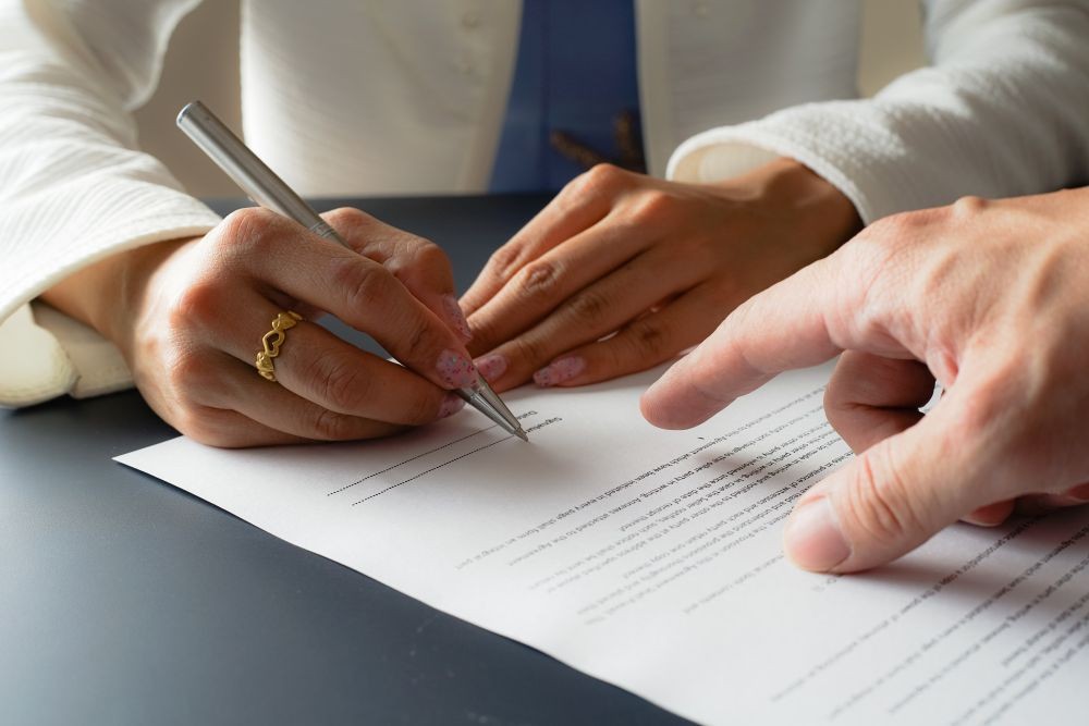 Image of two hands signing a legal contract.