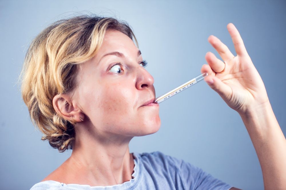Image of a woman with a thermometer in her mouth.
