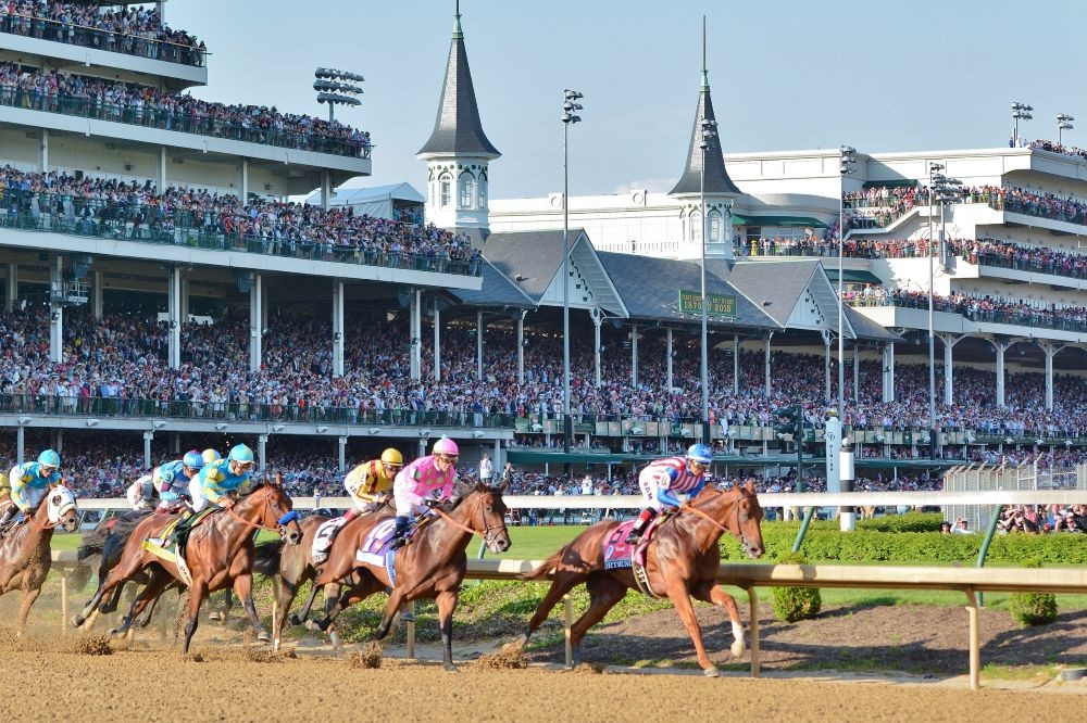 Photo of thoroughbred horses rounding at turn at Churchill Downs during the Kentucky Derby.