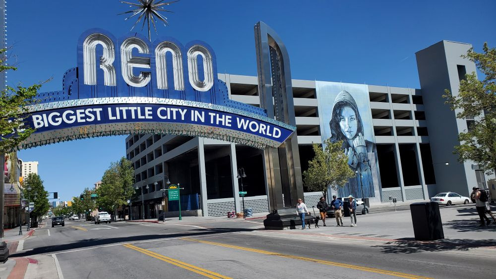 Photo Biggest Little City in the World sign with a mural on a parking garage on the right.