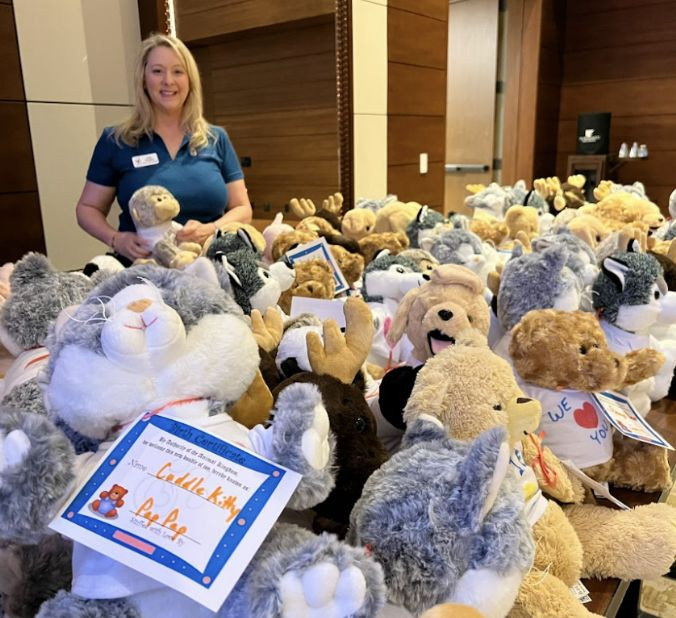 Woman standing with a bunch of stuffed animals for charity.