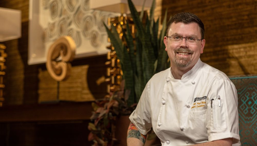 Chef Matthew Bishop sitting in a chair in his chef's uniform.